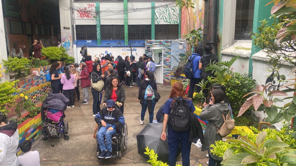Grupo de personas participando de elaboración de mural, en el grupo se observan algunas personas con discapacidad motora. 